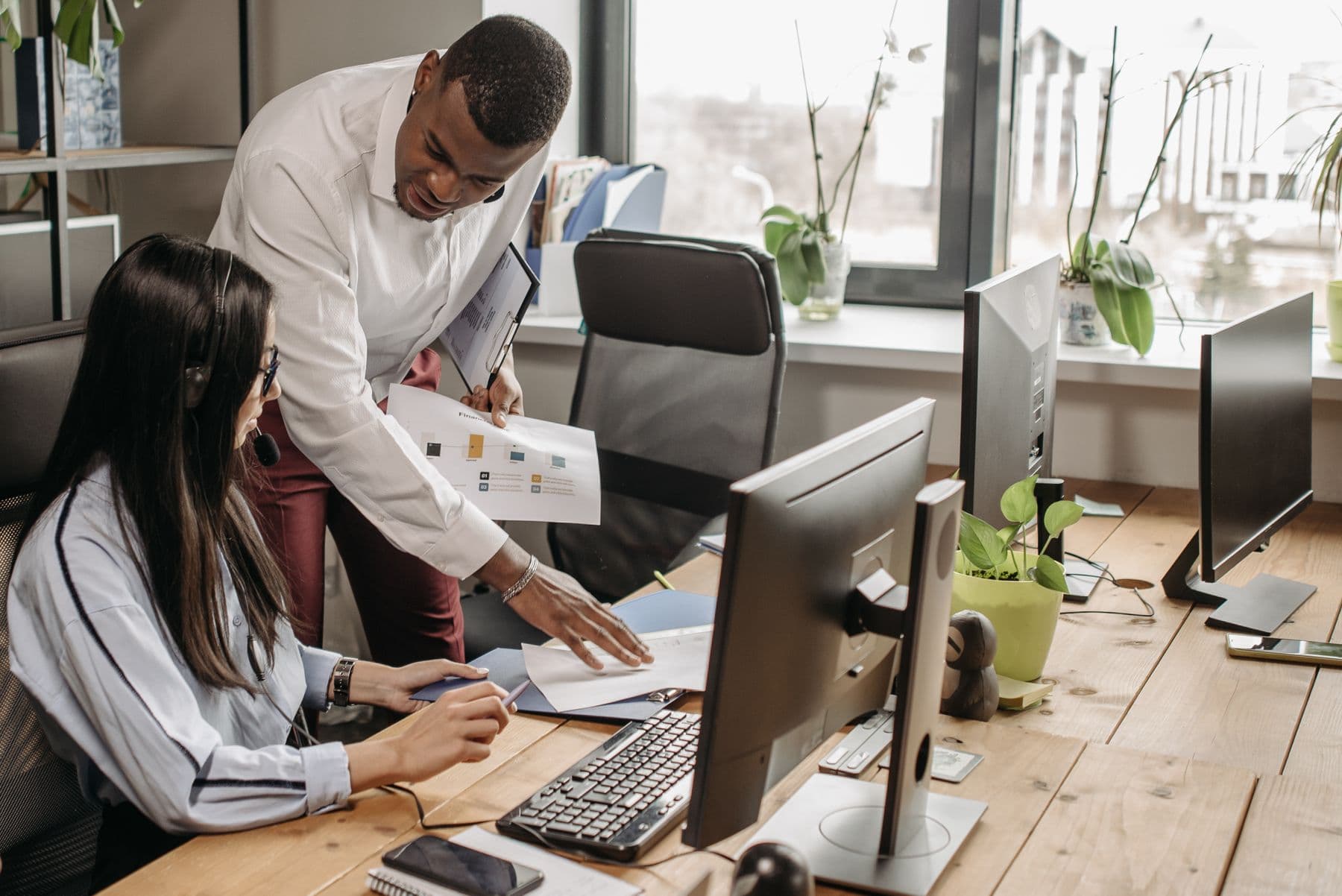 Two professionals reviewing a technology system together in a small office
