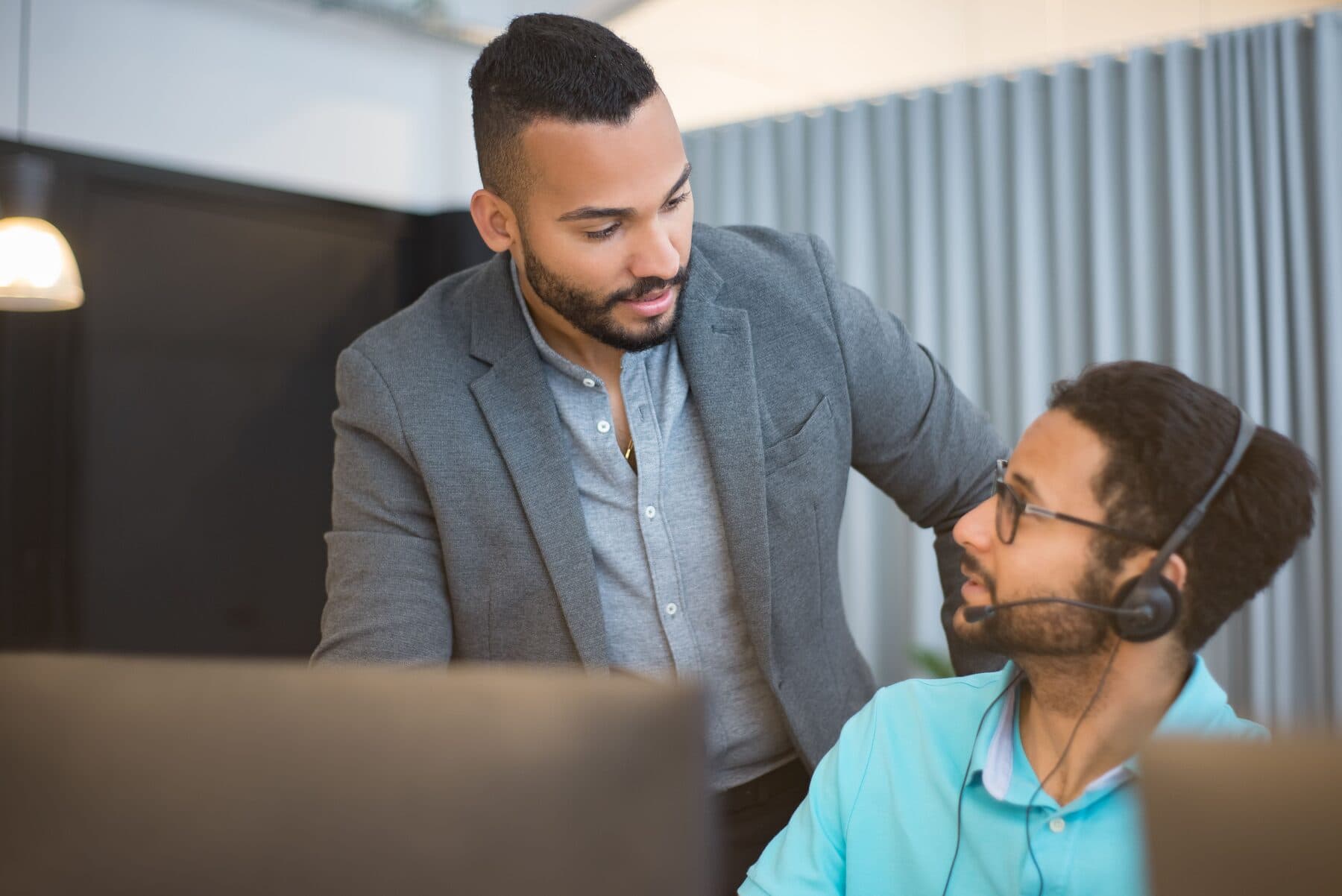 A technology professional reviewing plans with a client at an office computer
